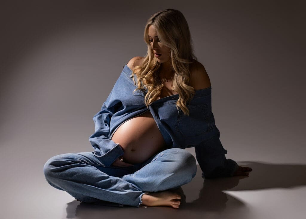 Pregnant woman sitting in a denim jacket and denim jeans